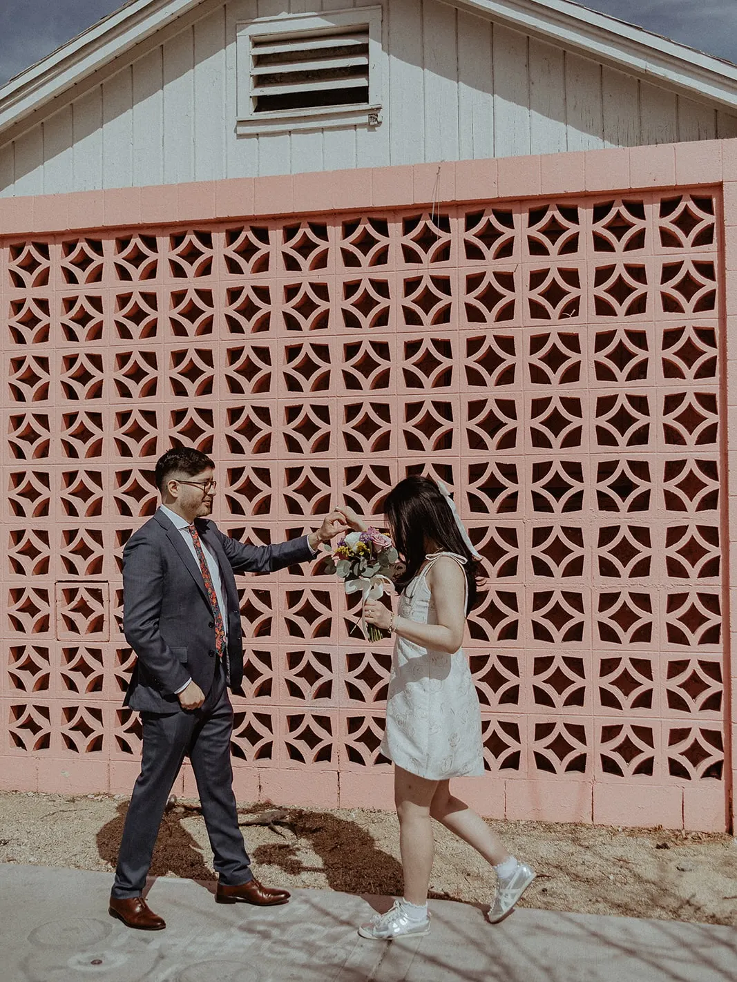 Las Vegas elopement couple against a pink mid-century wall